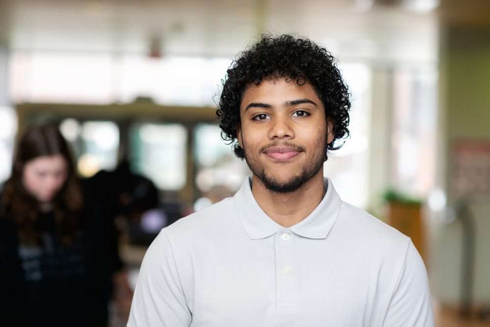 A headshot of a young man named Daniel Luna with dark, tight curly hair and a short beard, smiling at the camera.