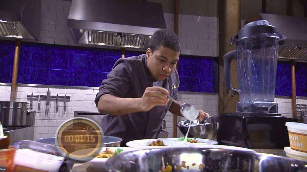 A candid action shot of the chef, Sakari Smithwick, cooking on the set of the television show Chopped.