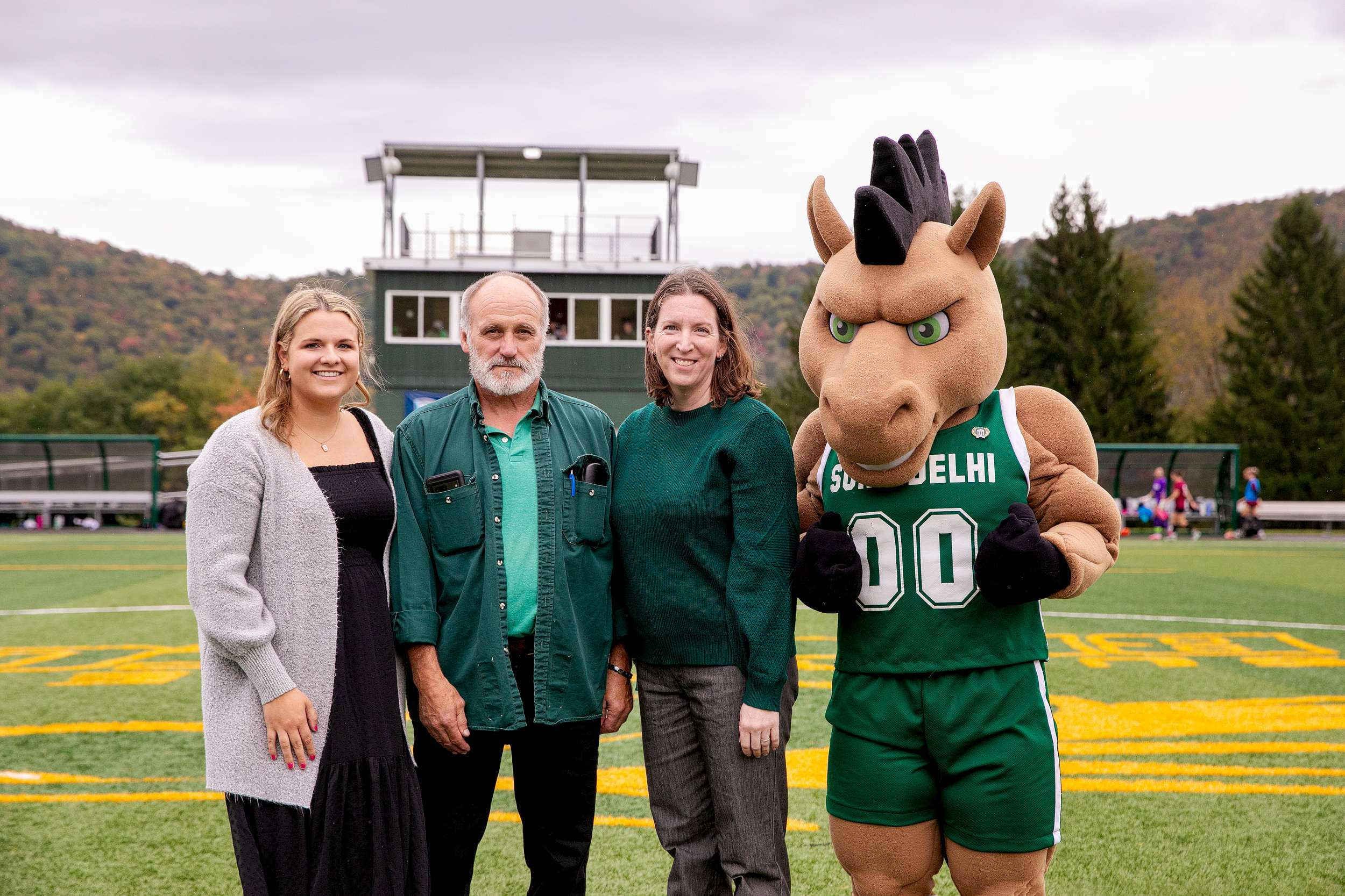 SUNY Delhi 2026 Hall of Fame recipients with the college mascot stand on the athletic turf on campus.