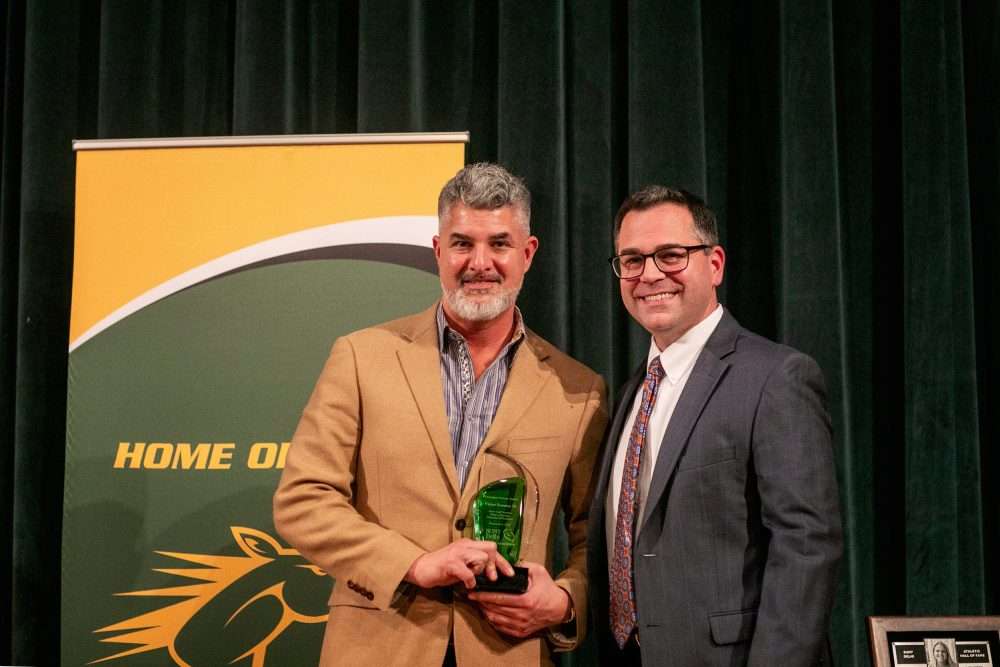 Victor Sommo poses with an alumni awards trophy next to Provost Brower.